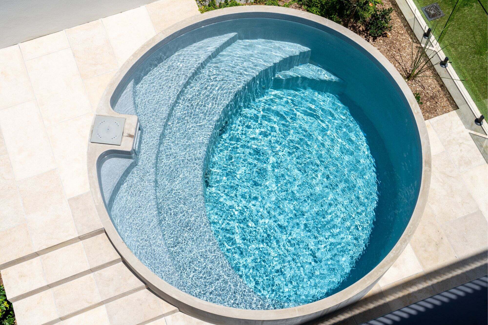 Plungie Arena, a circular plunge pool, in a Brisbane backyard. The pool is installed above ground, creating an architectural feature for this newly renovated space.